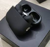Black wireless earbuds with charging case on a black surface