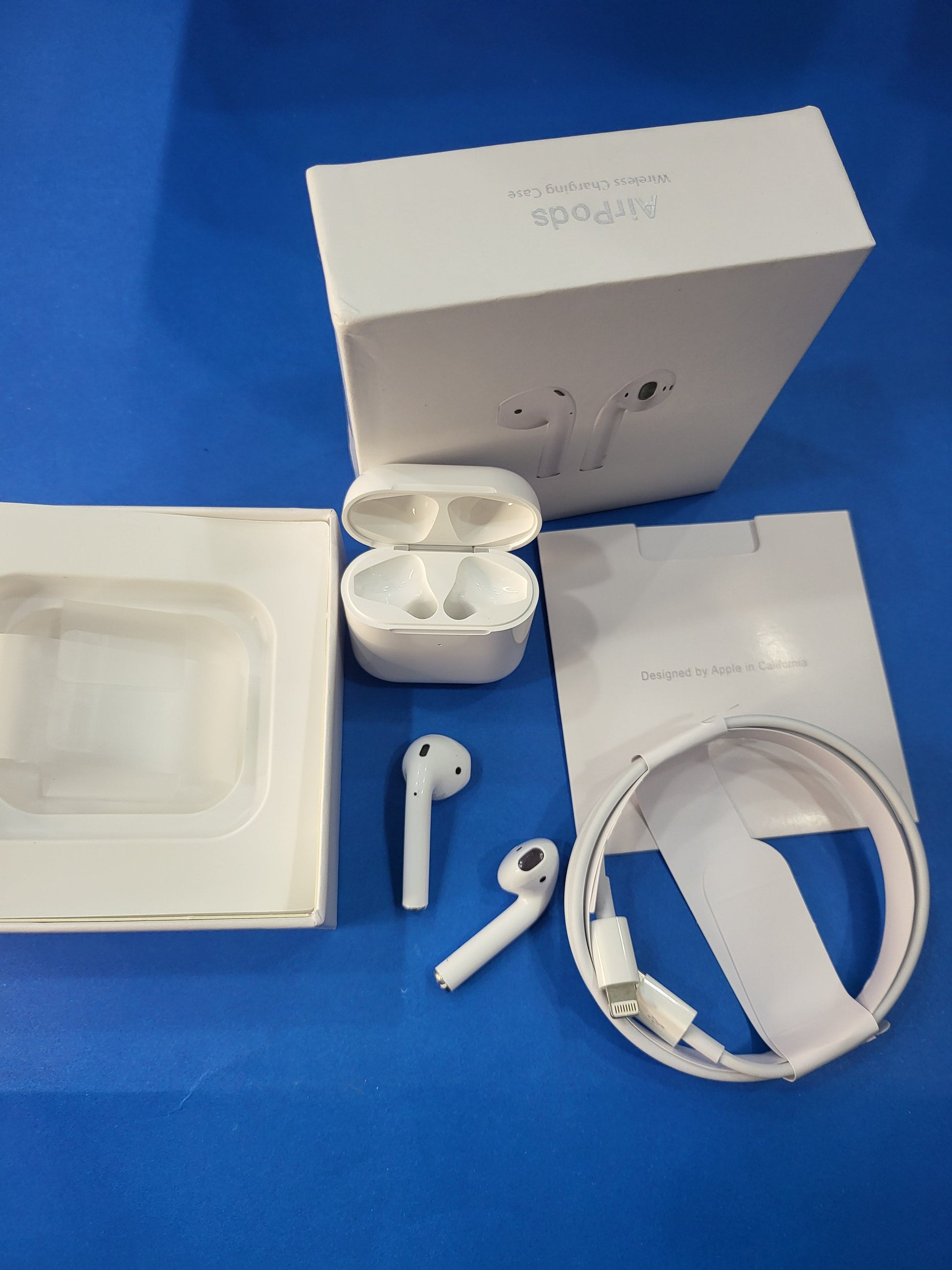 White wireless earbuds with charging case and cable on a blue background