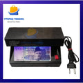 Black UV money detector with a Pakistani currency note on a white background, featuring Ittefaq Trading logo.